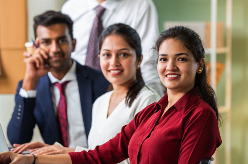 Indian asian young business professionals using laptop on desk discussing strategy
