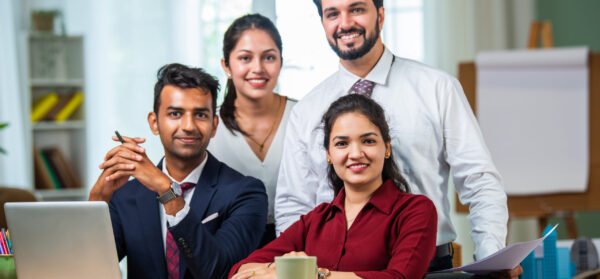 Indian asian young business professionals using laptop on desk discussing strategy